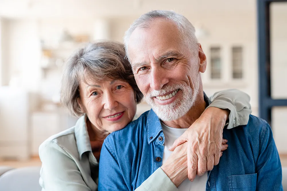 Senior couple looking at camera while hugging